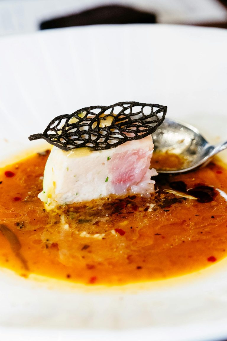 A gourmet fish fillet delicately plated with a rich sauce and decorative garnish, showcasing fine dining elegance.
